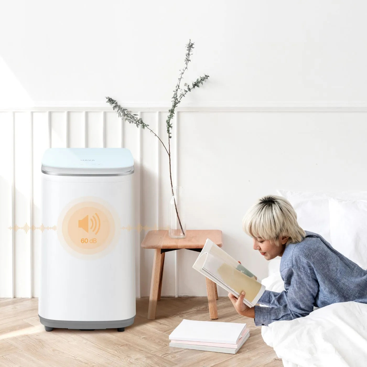 HAVA tvättmaskin från Go-clean.se i ett tyst hemmiljöscenario med endast 60 dB ljudnivå, medan en person läser avslappnat bredvid.