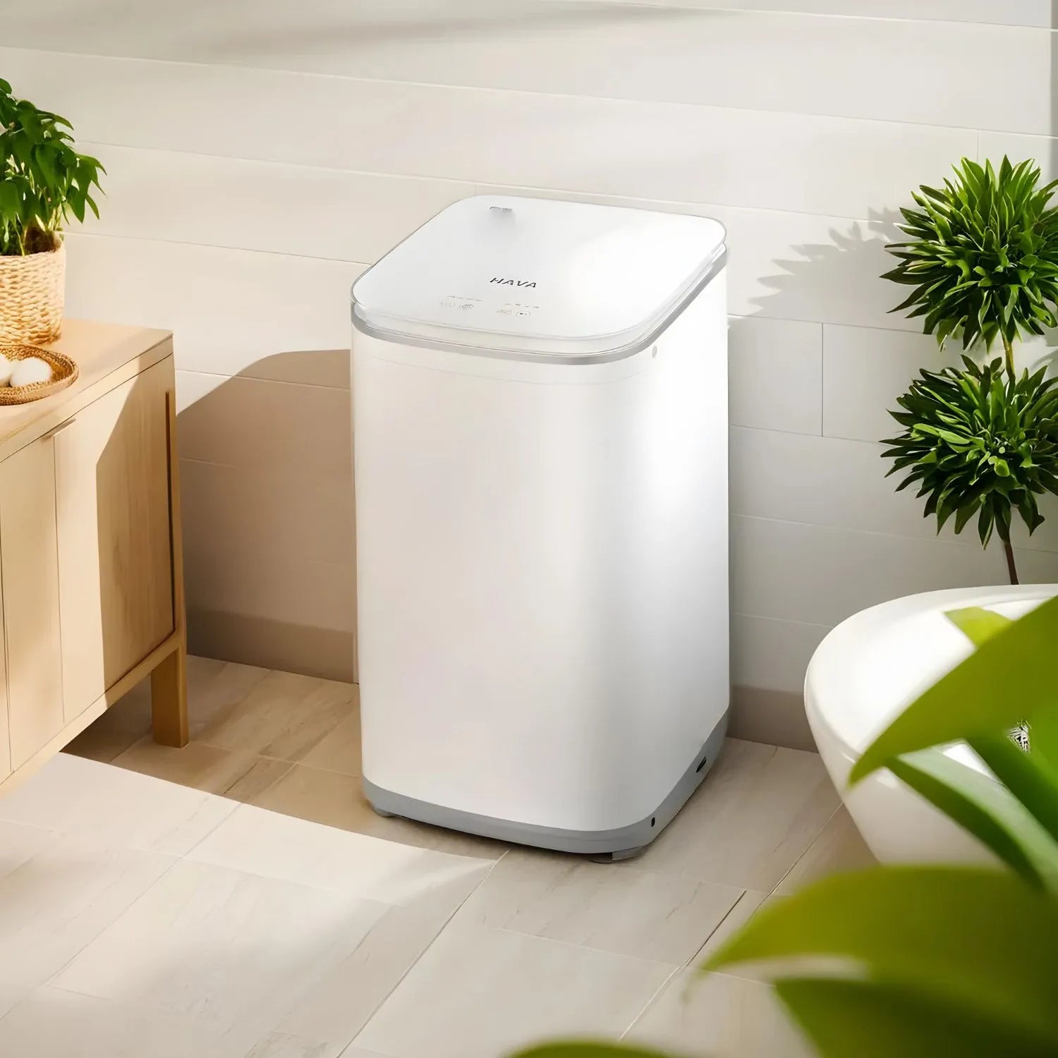 HAVA tvättmaskin från Go-clean.se placerad på ett ljust klinkergolv i badrum med växt på skåp och frodig växt i förgrunden, som förmedlar en fräsch och avkopplande miljö.