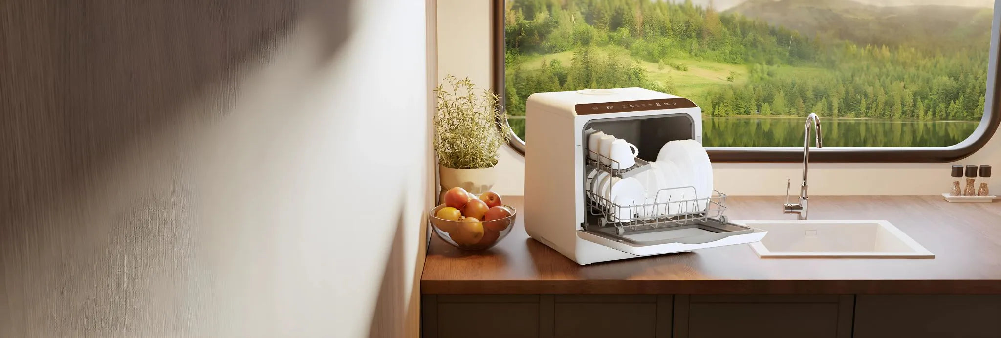 HAVA Bänkdiskmaskin från Go-clean.se på en träbänk i köket, intill en skål med frukt och en örtkruka, med öppet fönster mot sjö- och skogsmiljö i bakgrunden.