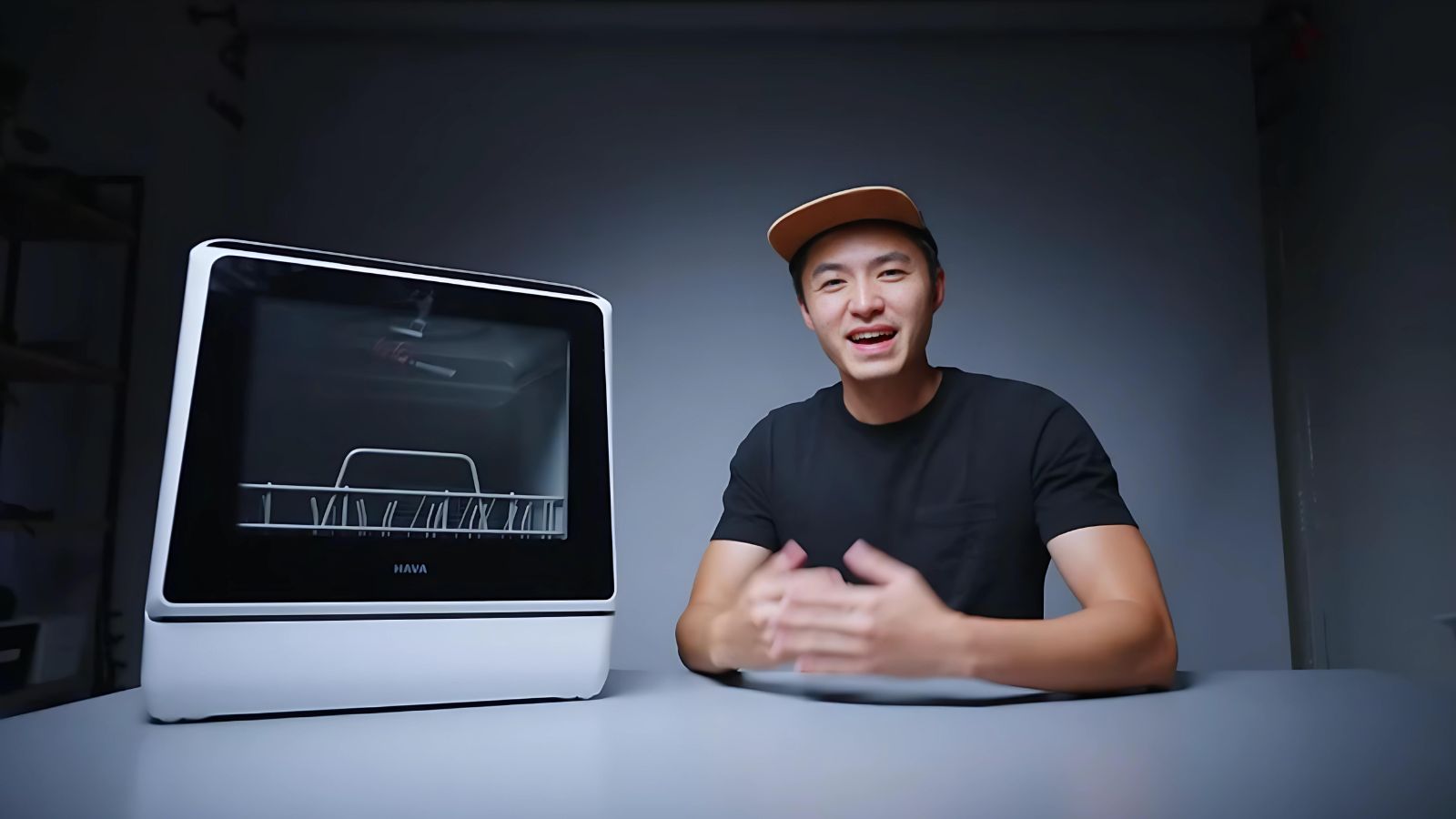 Leende person demonstrerar Go-clean Hava bänkdiskmaskinens funktioner, med maskinen tydligt synlig och redo för diskning.